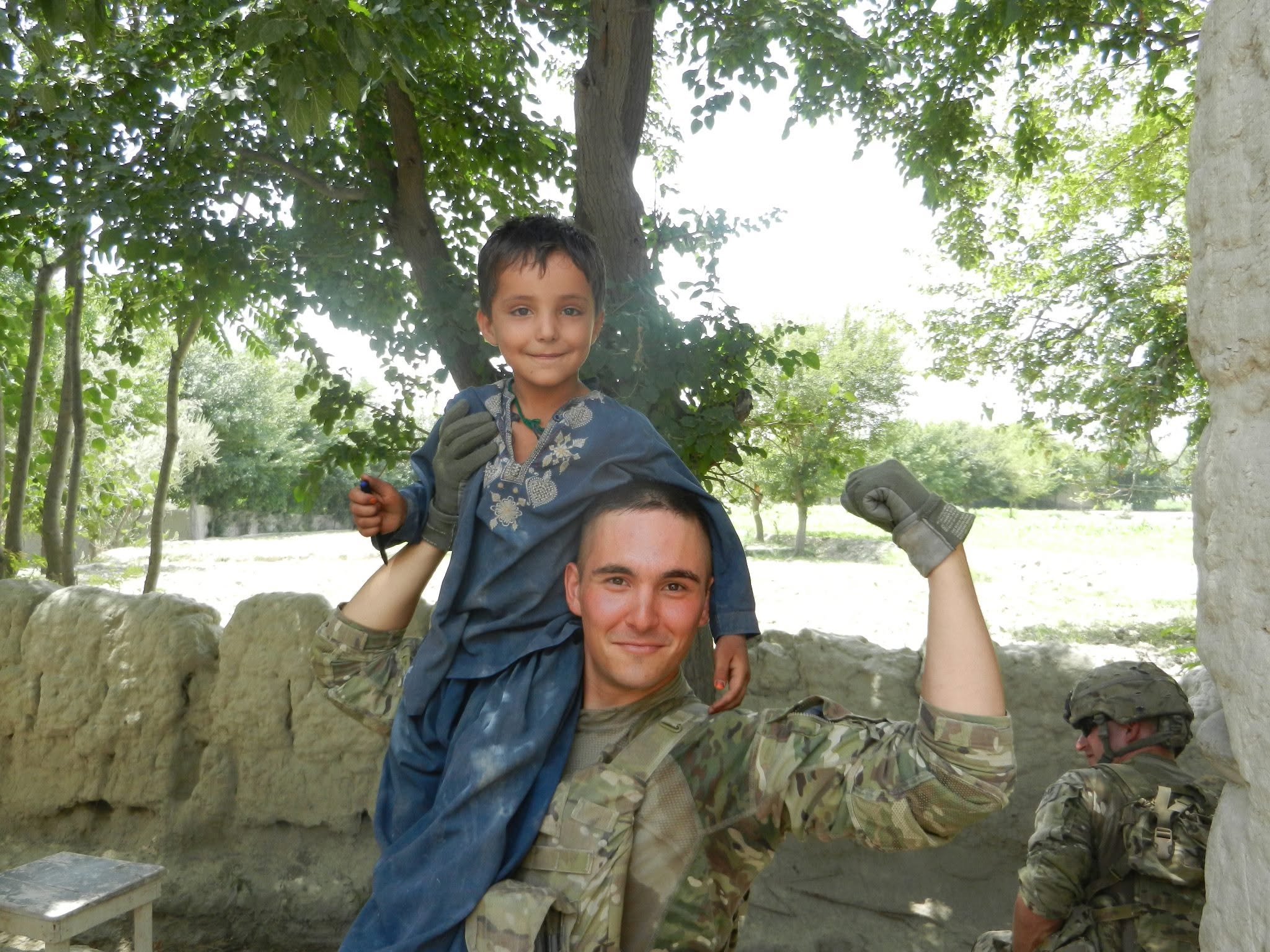 Onur Oncer carrying an Afghan child on his shoulders during a deployment